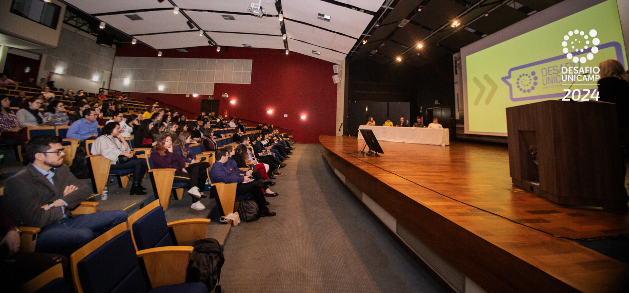 Na imagem, auditório utilizado na final de uma edição anterior do Desafio Unicamp 2024 com o publico à esquerda e o palco à direita.