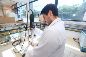 João Luís Faneco Paschoa é um homem jovem branco, ele está de costas para a foto, veste jaleco branco e mexe em equipamento misturador no laboratório da FEA Unicamp onde a emulsão gel foi desenvolvida. Fim da descrição.