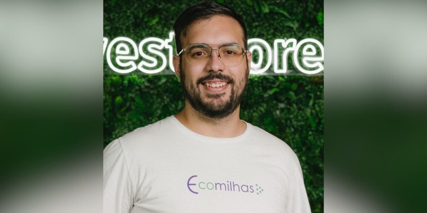 : Fotografia colorida de um colaborador da Ecomilhas posando para a foto. Ele está sorrindo, uniformizado e olhando diretamente para a câmera. Fim da descrição.