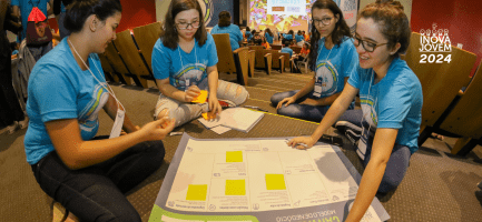 Na imagem, alunos participantes do Inova Jovem se reúnem e preenchem juntos um Business Model Canvas.