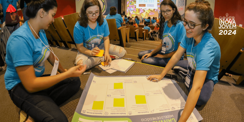 Na imagem, alunos participantes do Inova Jovem se reúnem e preenchem juntos um Business Model Canvas.