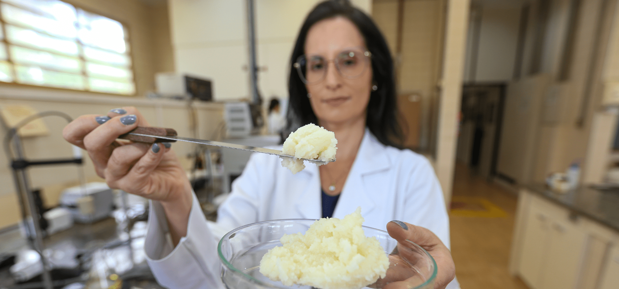 A imagem mostra a professora Ana Paula Badan, no Laboratório de Óleos e Gorduras da Unicamp, segurando a gordura obtida a partir do óleo de macaúba. Fim da descrição.