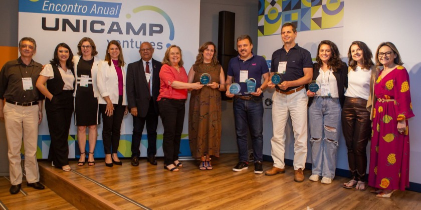 Fotografia colorida de pessoas sendo premiadas no Prêmio Empreendedor da Unicamp 2023. Todas estão em pé e posando para a foto.