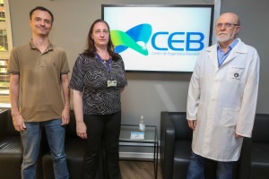 A imagem mostra os autores da tecnologia: Eder Trevisoli da Silva (CEB), Ana Cristina Bottura Eboli (CEB) e José Wilson Magalhães Bassani (FEEC). Eles estão posicionados para a foto em frente a uma televisão ligada com o logo da CEB. Fim da descrição.