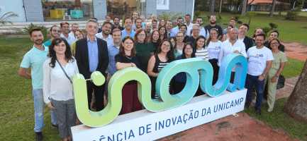 Na imagem, membros de empresas-filhas, incubadas e da equipe da inova posam para a foto em frente a placa na sede da Inova Unicamp