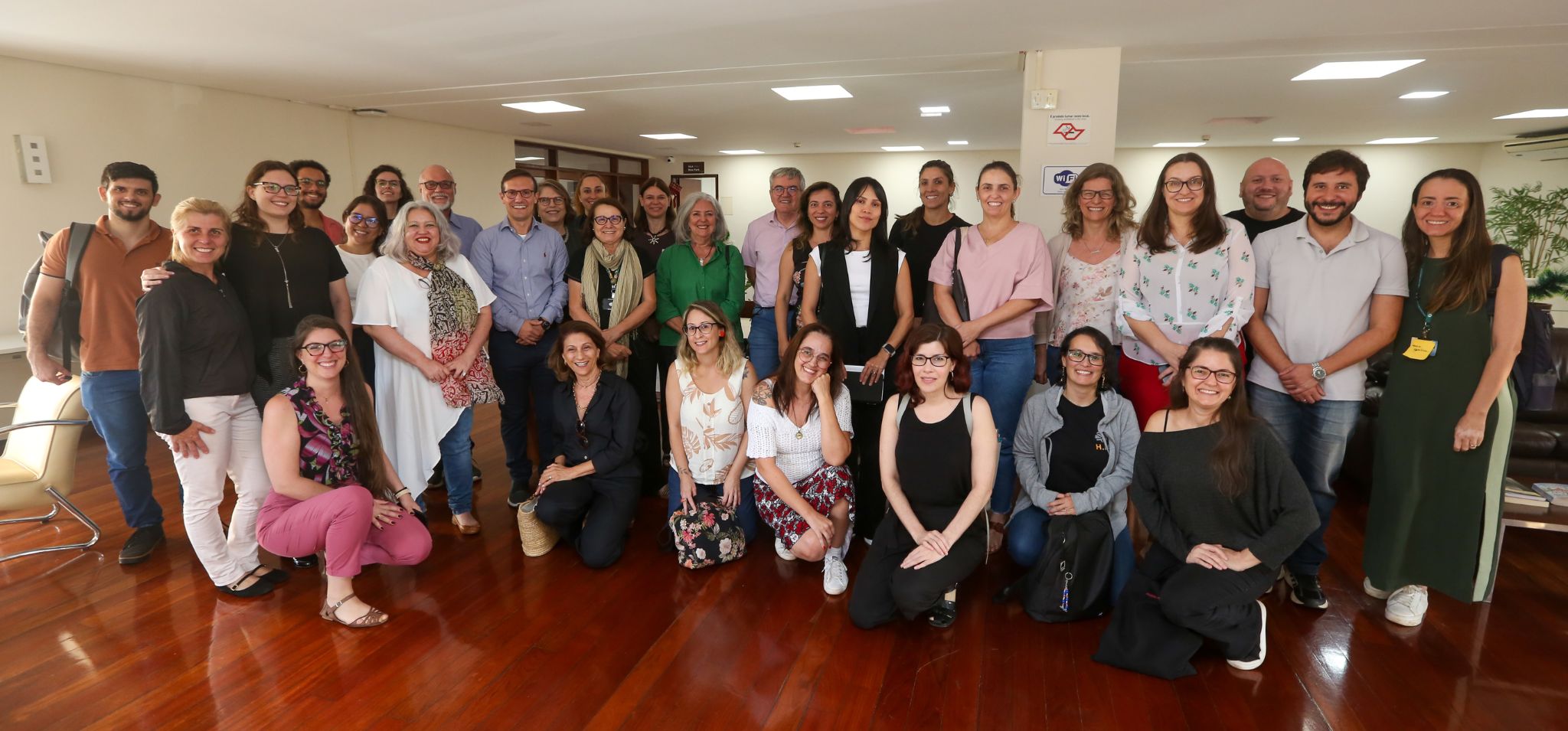 Foto colorida com cerca de vinte pessoas lado a lado