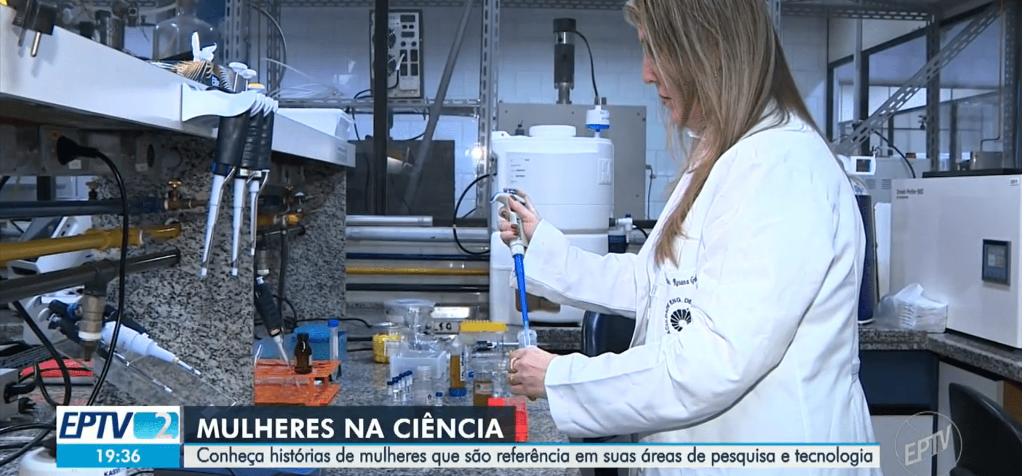 A imagem mostra uma pesquisadora mulher em seu laboratório. A imagem também contém uma legenda: Mulheres na ciência - Conheça histórias de mulheres que são referência em suas áreas de pesquisa e tecnologia. Fim da descrição.